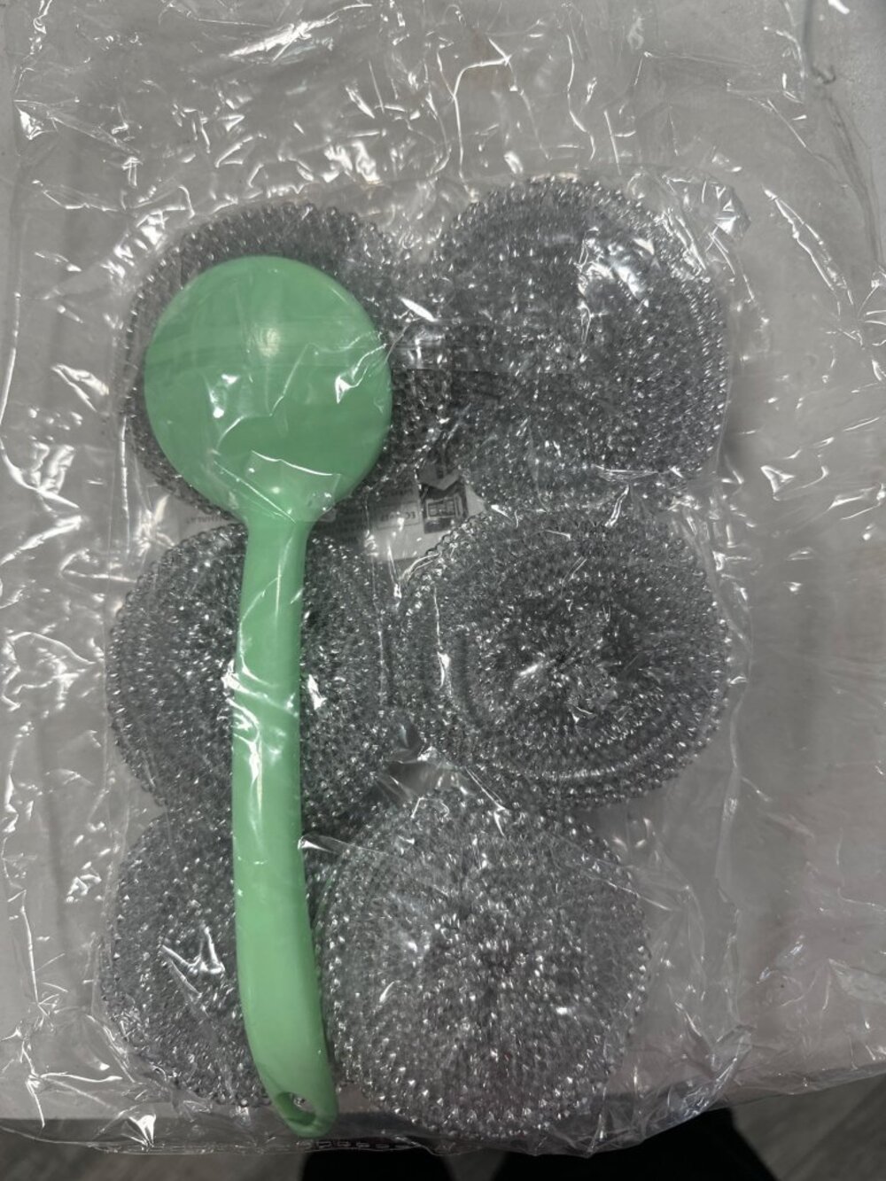 6 esponjas de acero alrededor del mango verde , destacando la textura metálica d